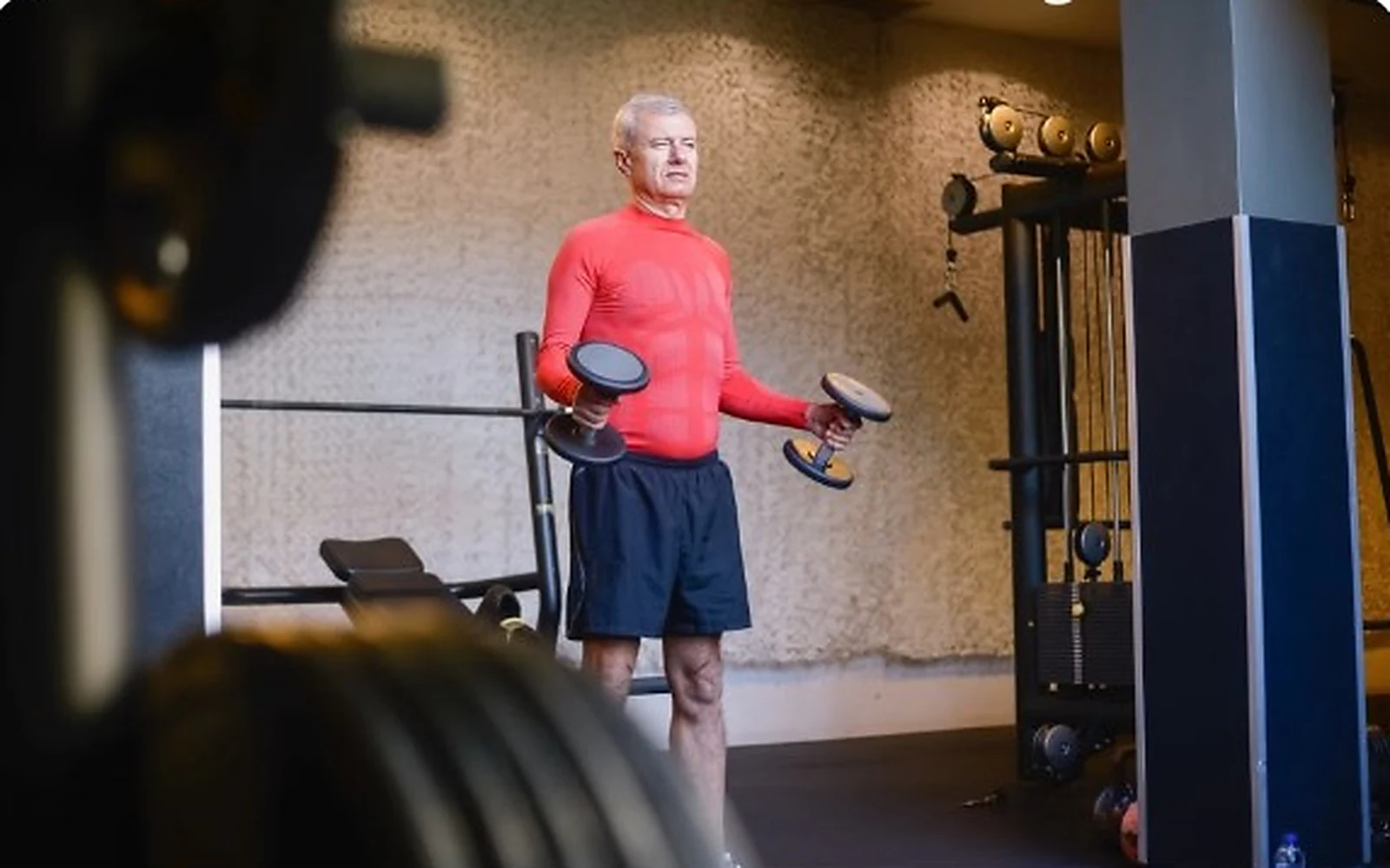 Older adult strength training with dumbbells in a gym, representing strength and capability after 40.