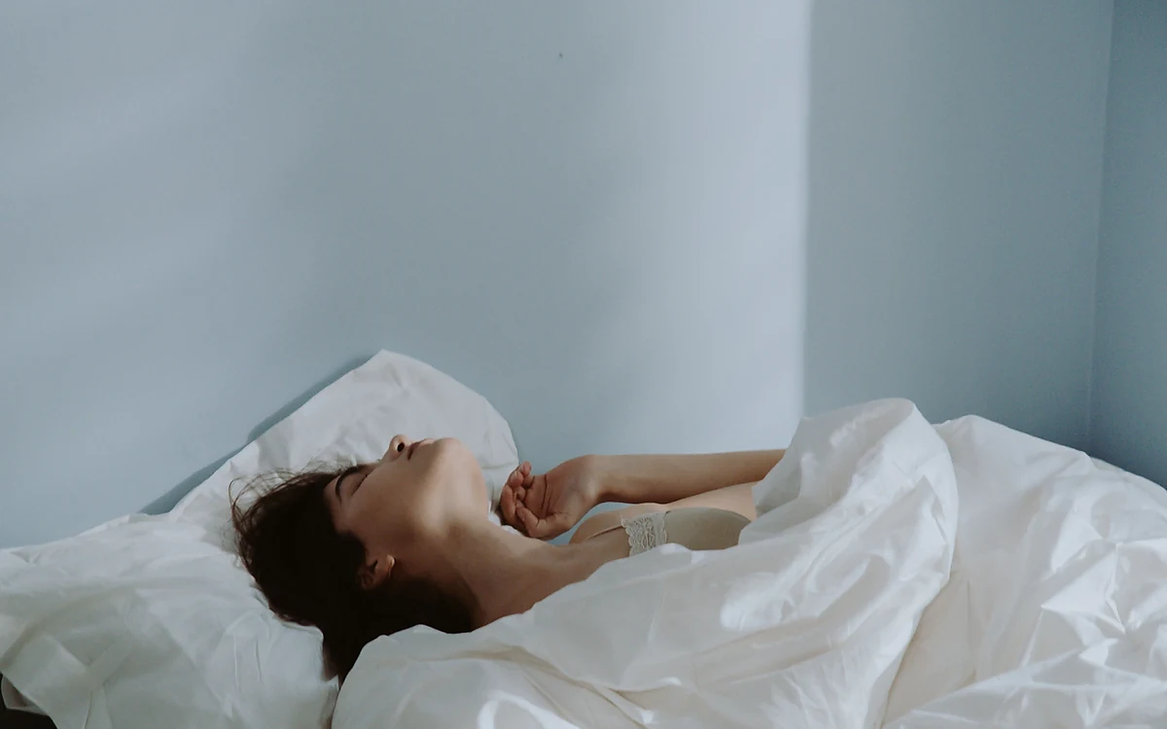 Woman resting peacefully in bed, representing sleep and recovery.