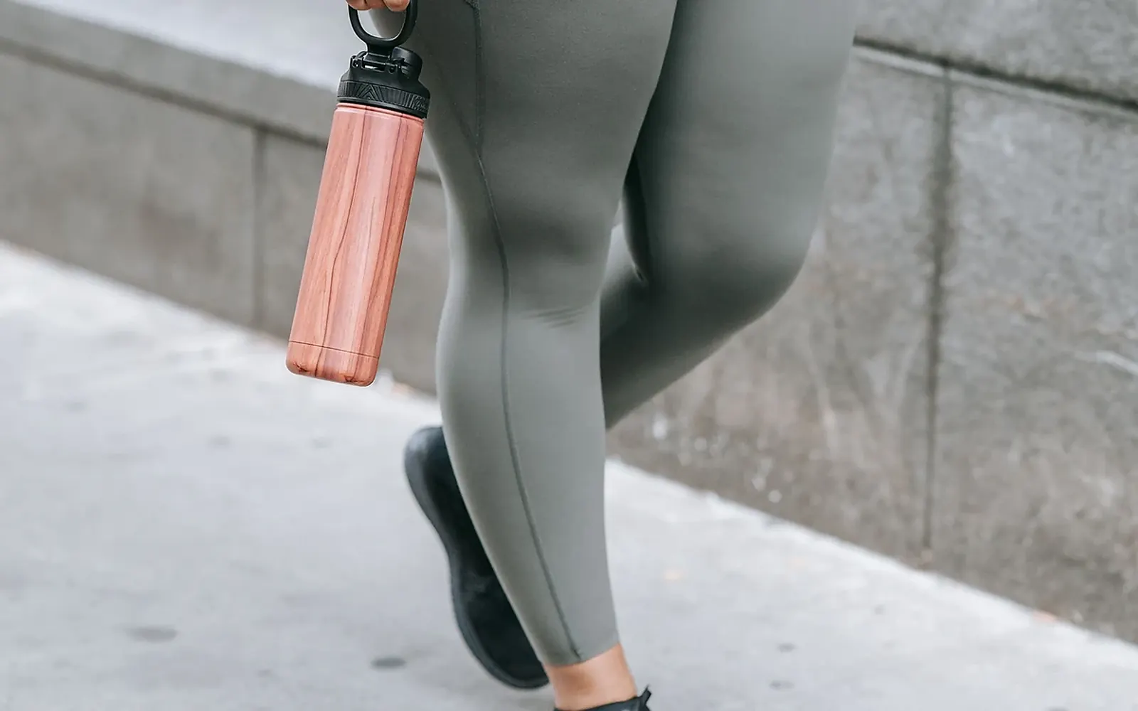 Person walking with a water bottle, representing practical everyday healthy habits.