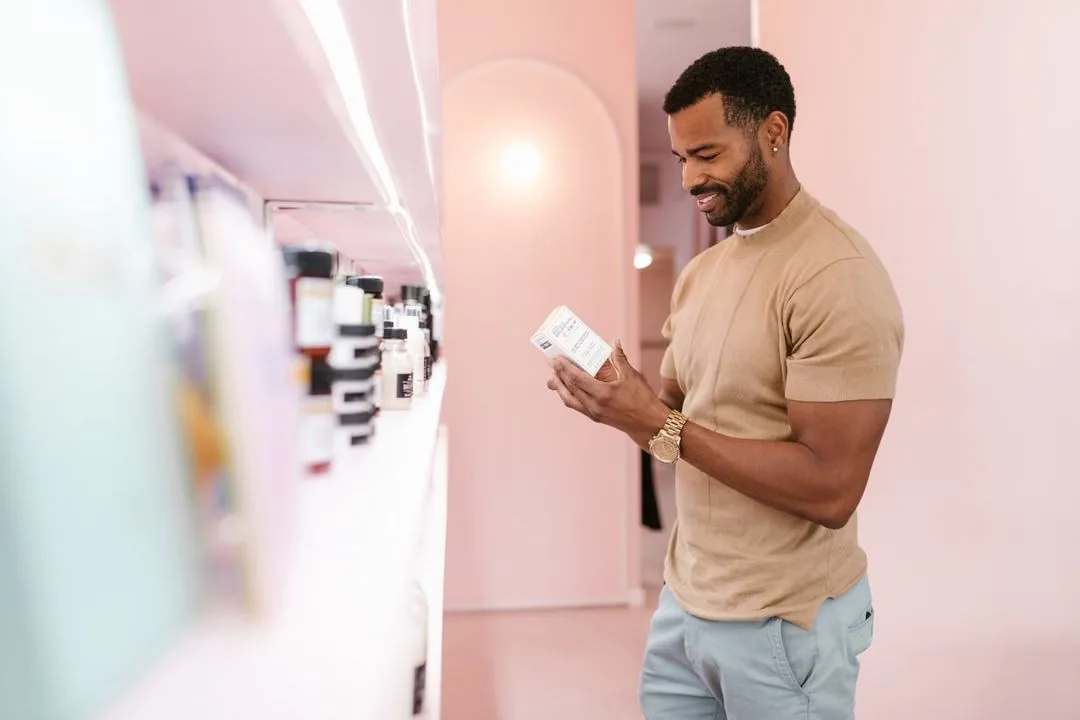 Man reading a product label in a store aisle.