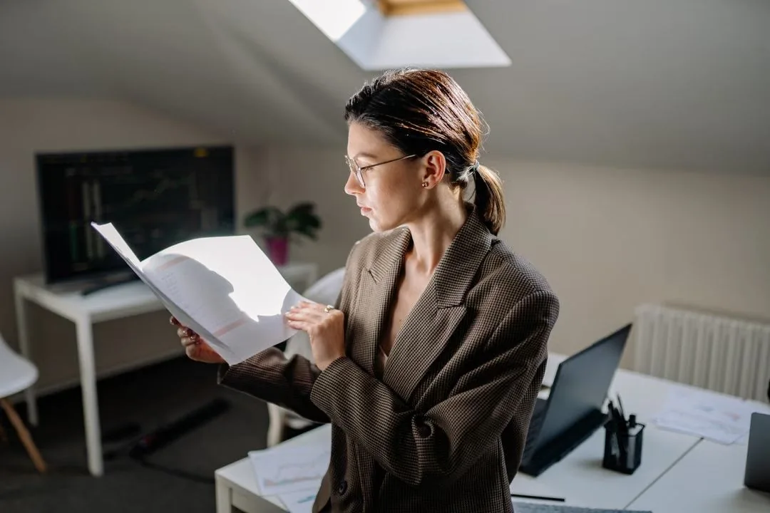 Woman reading printed pages in an office.