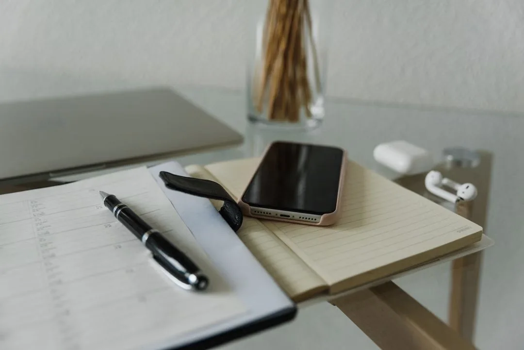 Notebook, pen and smartphone arranged on a desk.