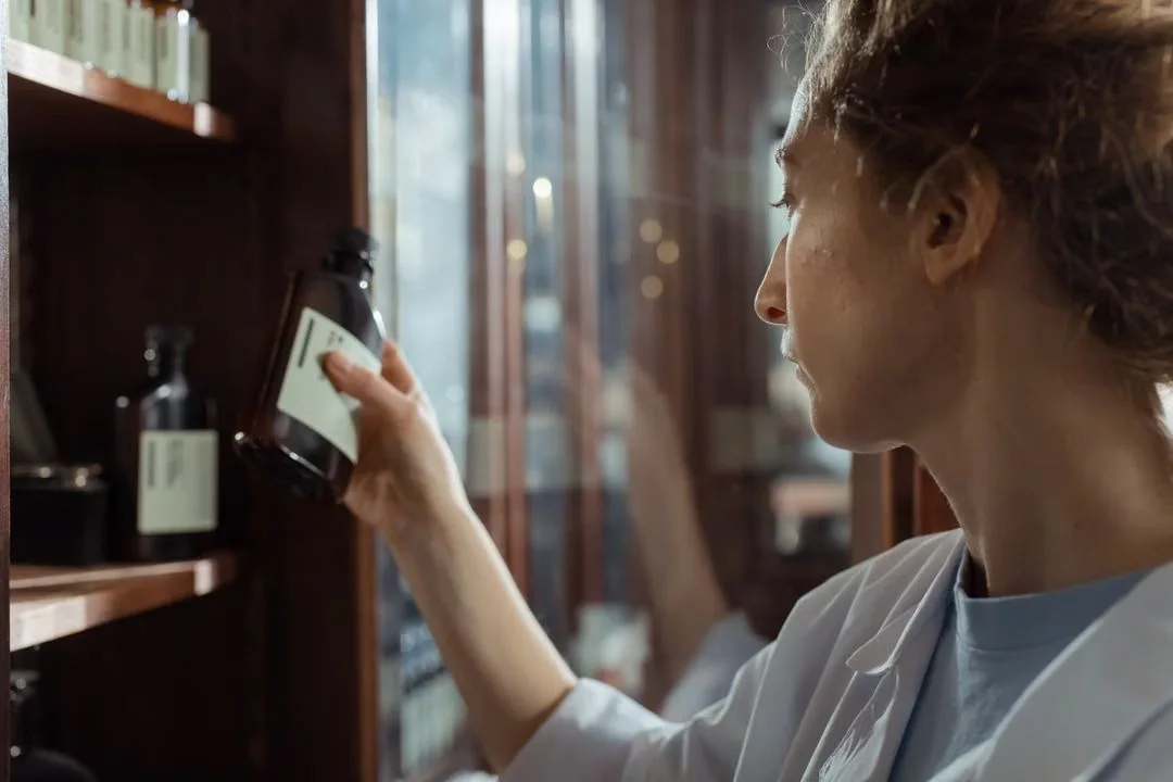 Woman reading the label on a bottled product at a shelf.