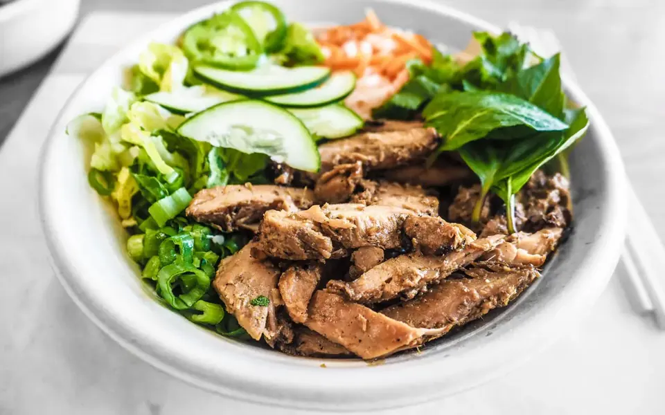 Sliced meat and vegetables in a white bowl