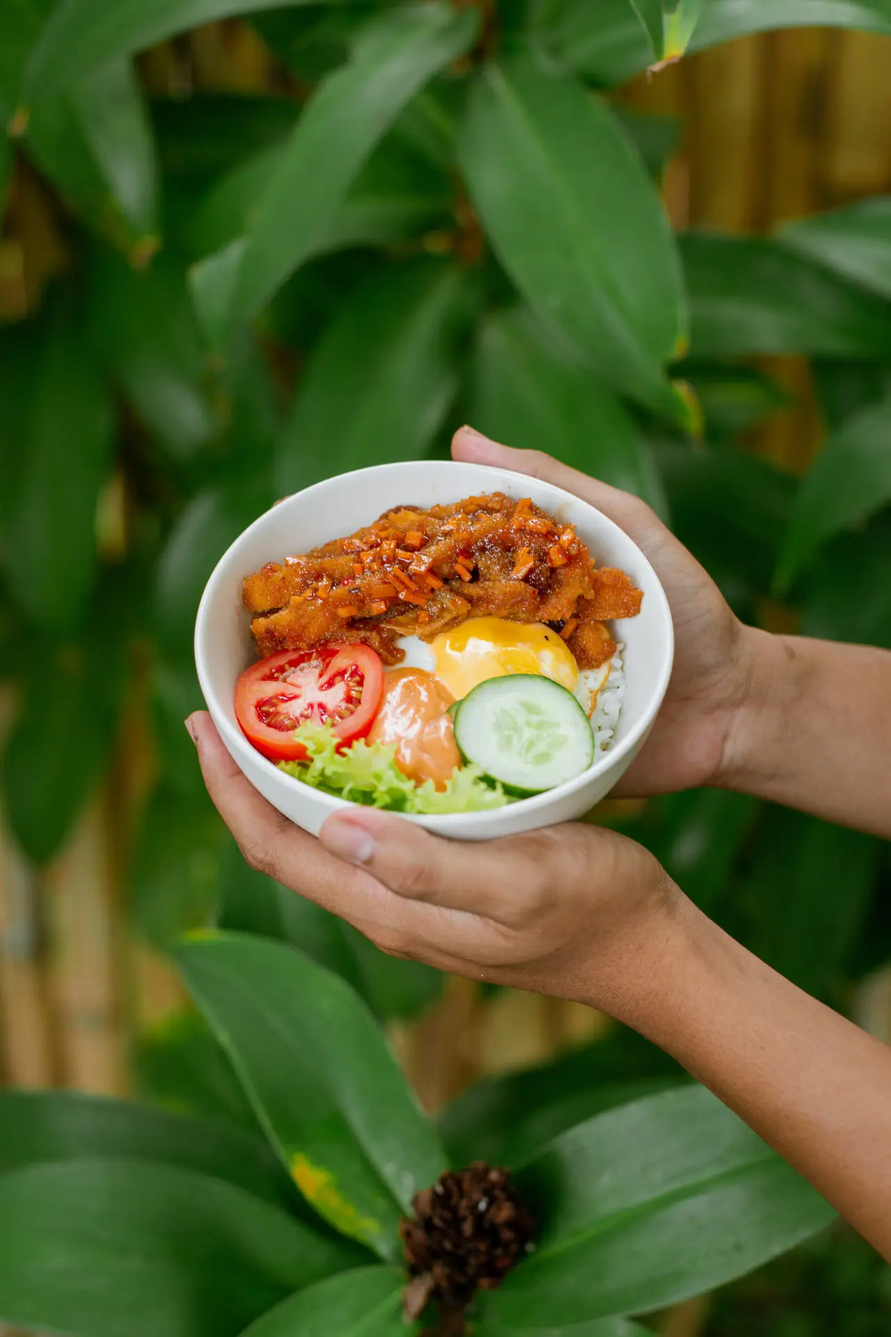 Fresh protein and vegetable bowl held outdoors.