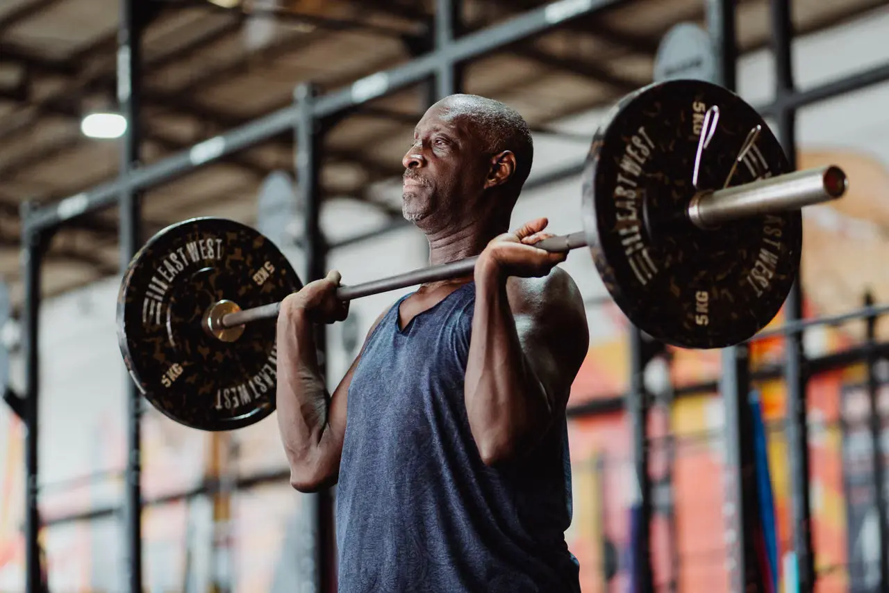 Senior man lifting a barbell during strength training.
