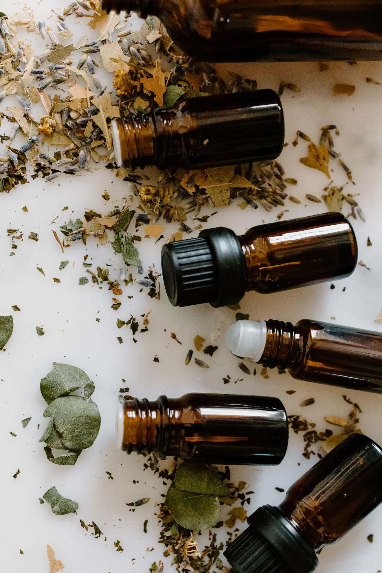 Amber glass bottles and dried herbs on a white surface